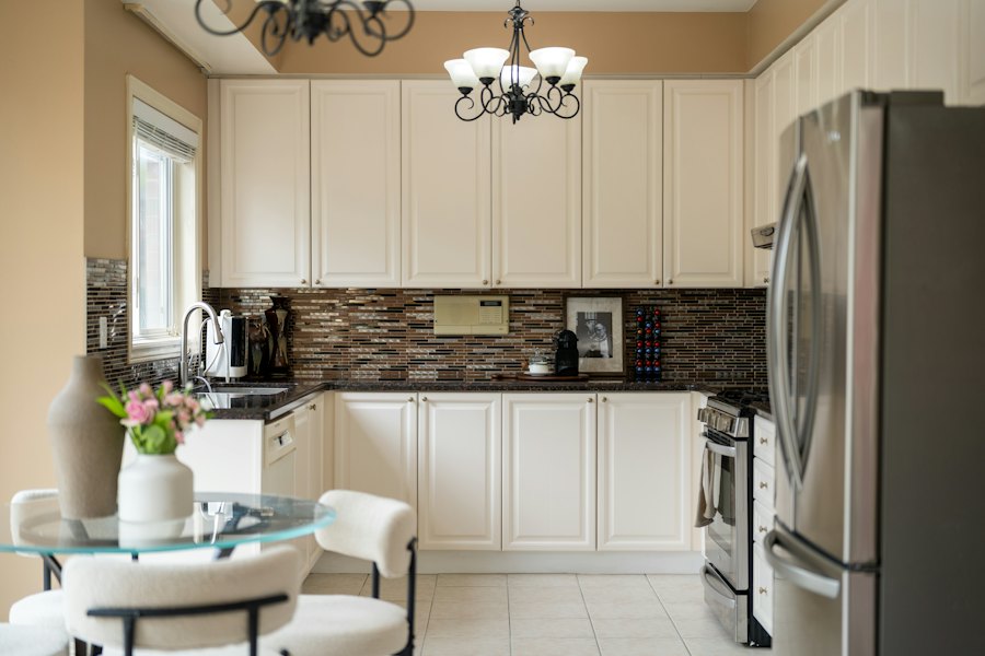 Kitchen with cream cabinets, tile backsplash, and stainless steel appliances